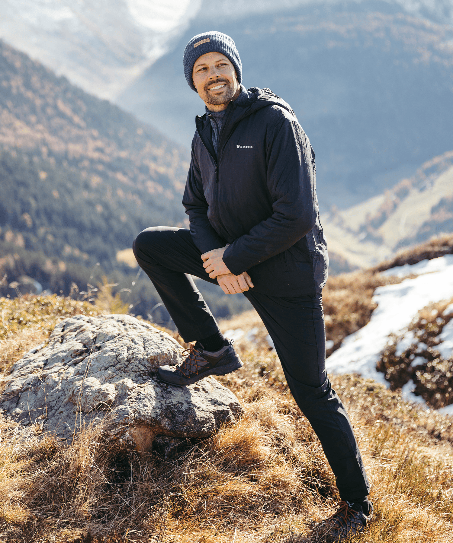 Model trägt die BERGMENSCH Herren Thermolite Jacke in Schwarz und die Cozy Fleece Beanie in Midnight Navy